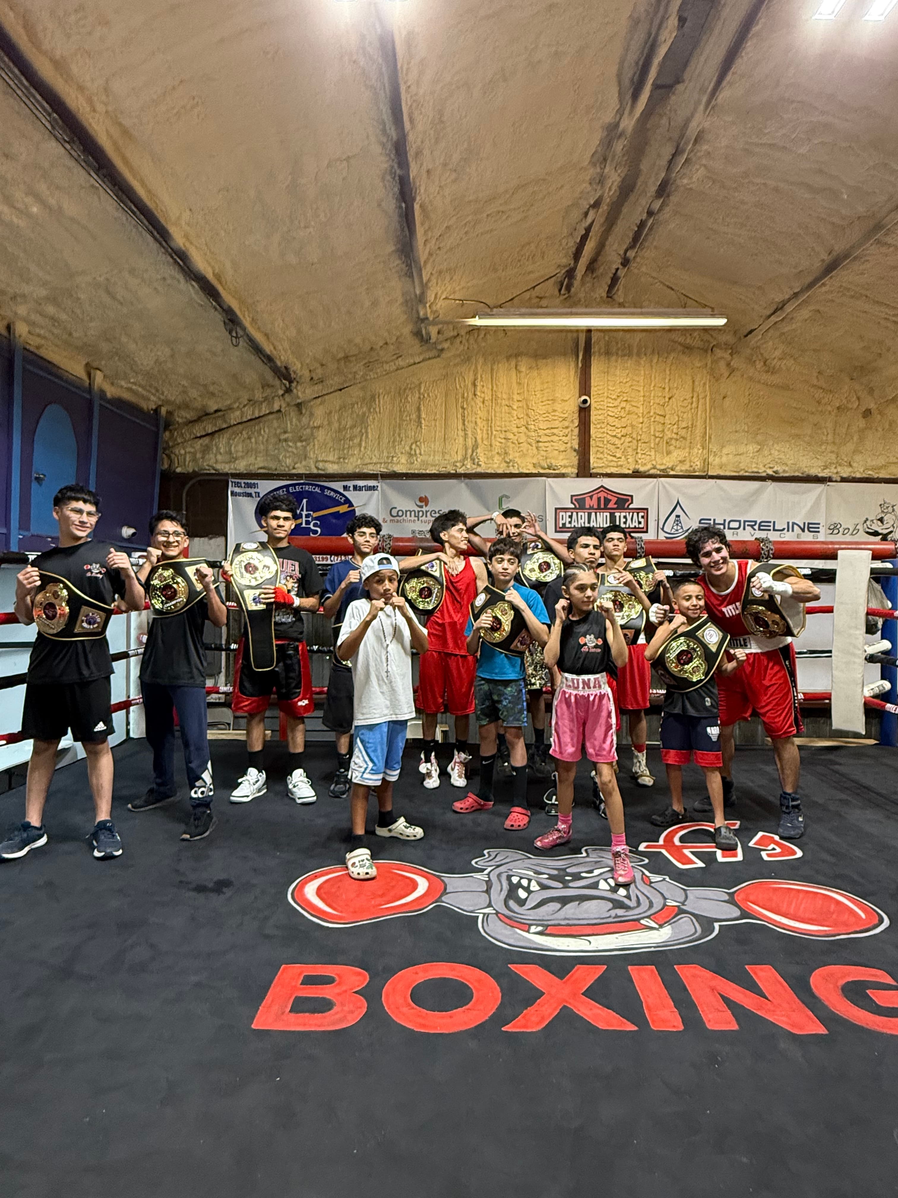 A gym team in the ring holding championship belts